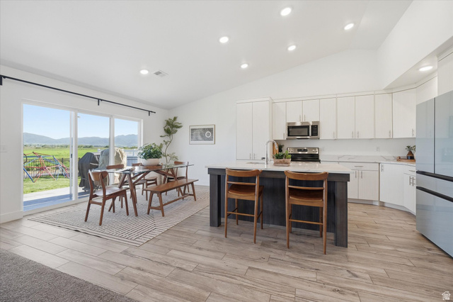 1422 West 3410th Street South Logan, UT 84321 - Photo 7 of 33 Open-concept kitchen and dining area featuring a vaulted ceiling and wood-finish flooring