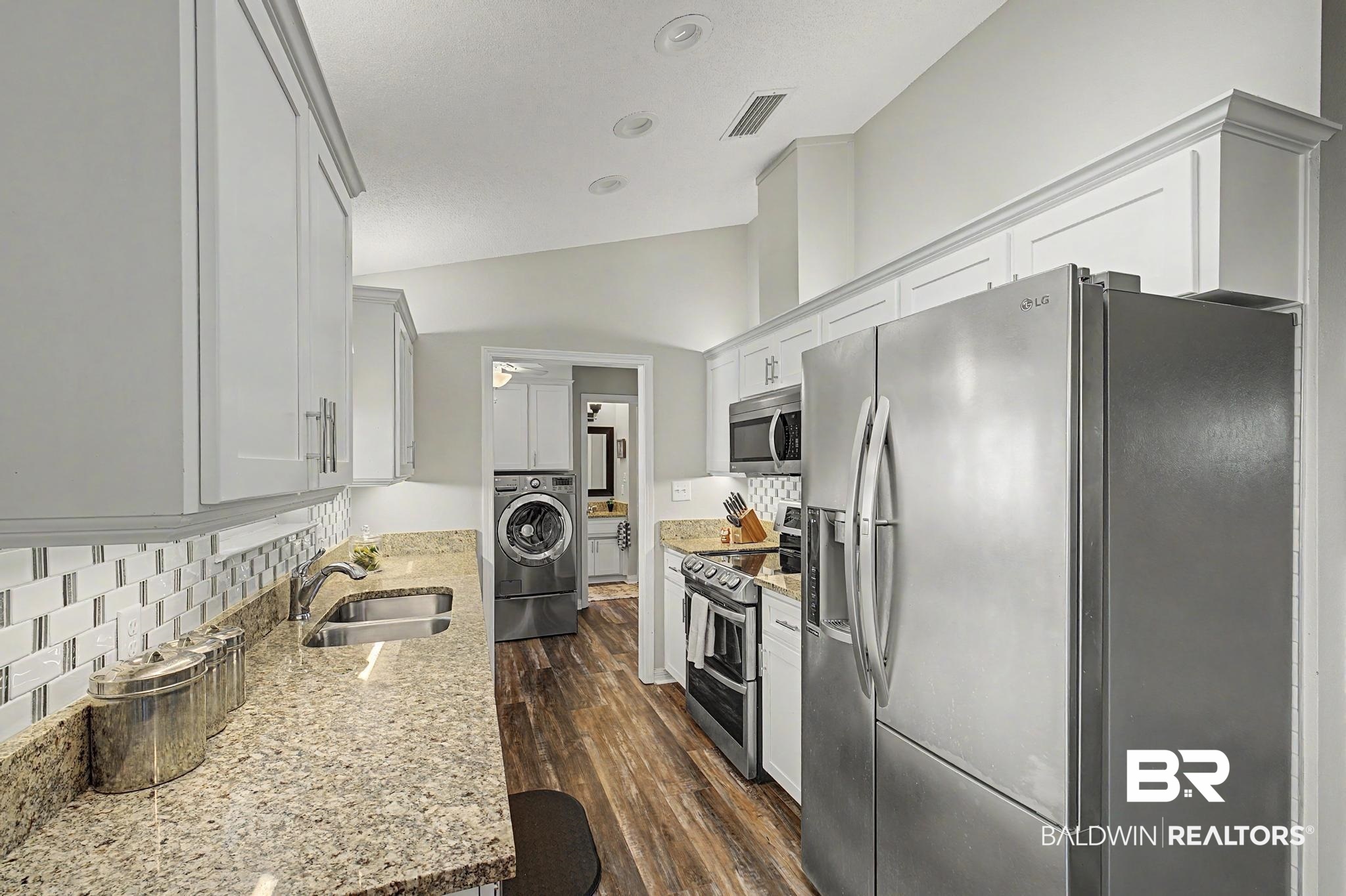 2808 Pine Ridge Drive Lillian, AL 36549 - Photo 15 of 47 Kitchen featuring wood-finish flooring, light cabinetry with crown molding, and granite countertops