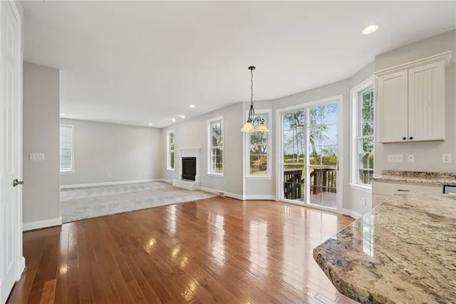 a kitchen with kitchen island granite countertop a refrigerator a sink dishwasher a stove and white cabinets with wooden floor