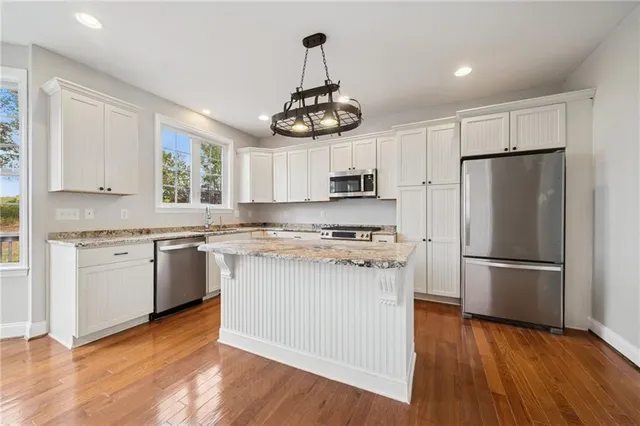 a kitchen with stainless steel appliances granite countertop a stove top oven a refrigerator a sink and dishwasher with wooden floor