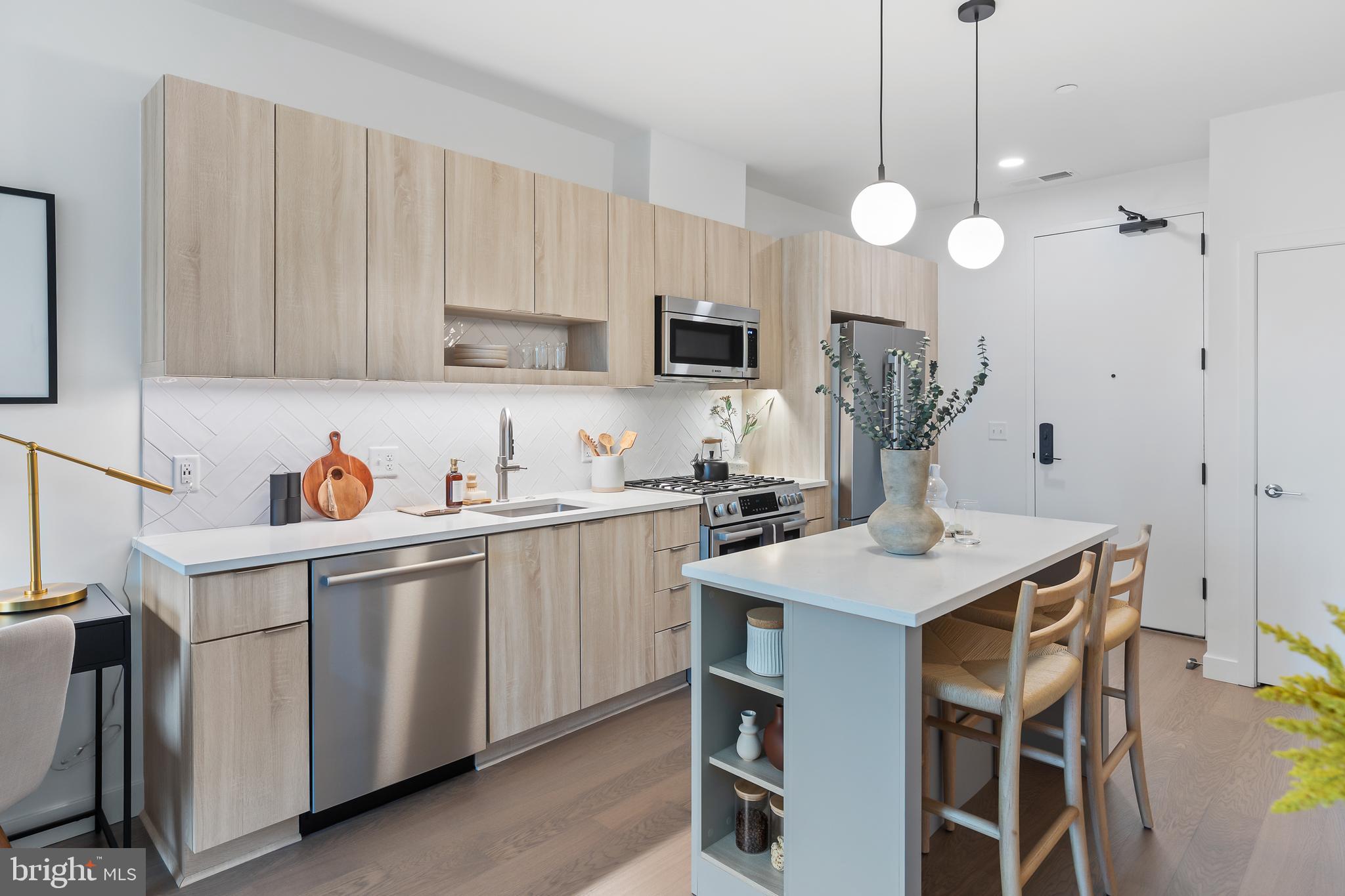 7175 12th Street Northwest, Unit 411 Washington, DC 20012 - Photo 2 of 46 a kitchen with stainless steel appliances kitchen island granite countertop a sink a microwave oven a stove and white cabinets