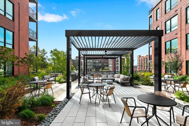 a view of a patio with table and chairs potted plants and floor to ceiling window