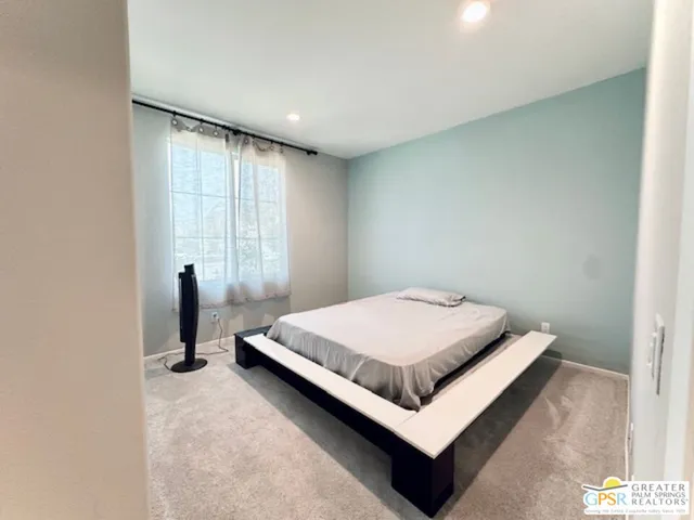 a bed sitting in a spacious bedroom next to a window