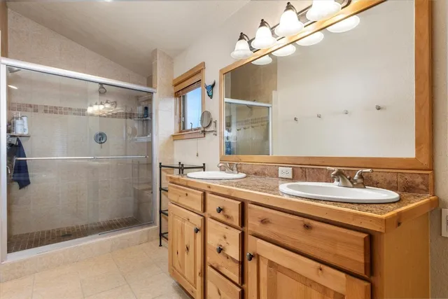 a bathroom with a double vanity sink mirror and shower