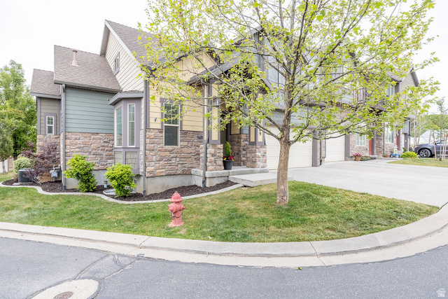 Multi-level exterior featuring stone veneer, horizontal siding, a bay window, and a concrete driveway