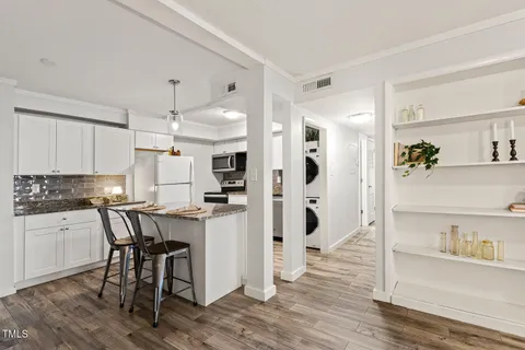 a kitchen with stainless steel appliances a dining table chairs refrigerator and sink