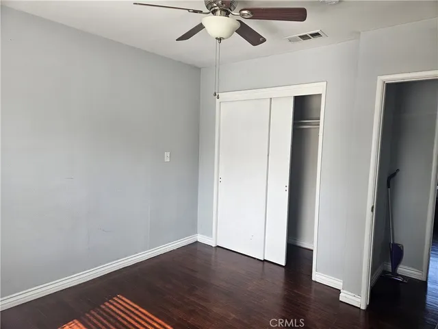 an empty room with wooden floor and ceiling fan