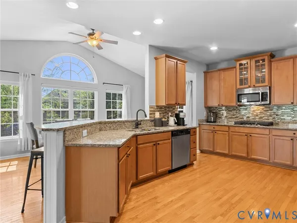 a kitchen with stainless steel appliances granite countertop a refrigerator a stove and a sink