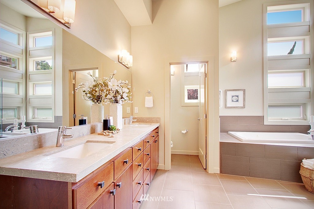 7757 Sand Point Way Northeast, Unit A Seattle, WA 98115 - Photo 16 of 25 a bathroom with a double vanity sink a mirror and a bathtub