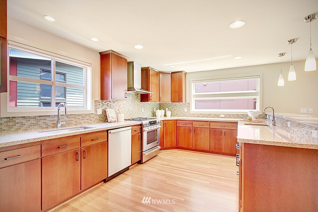 7757 Sand Point Way Northeast, Unit A Seattle, WA 98115 - Photo 4 of 25 a large kitchen with granite countertop a sink dishwasher stove and cabinets