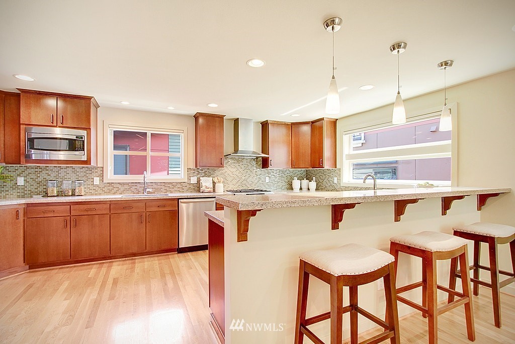 7757 Sand Point Way Northeast, Unit A Seattle, WA 98115 - Photo 5 of 25 a kitchen with stainless steel appliances granite countertop a sink a stove a refrigerator cabinets and chairs