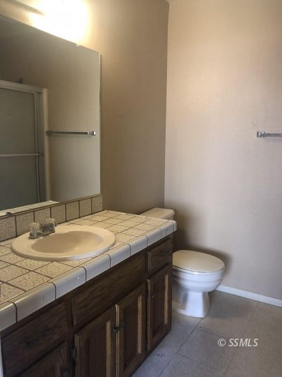 1004 West Graaf Avenue Ridgecrest, CA 93555 - Photo 13 of 21 a bathroom with a granite countertop toilet sink and mirror