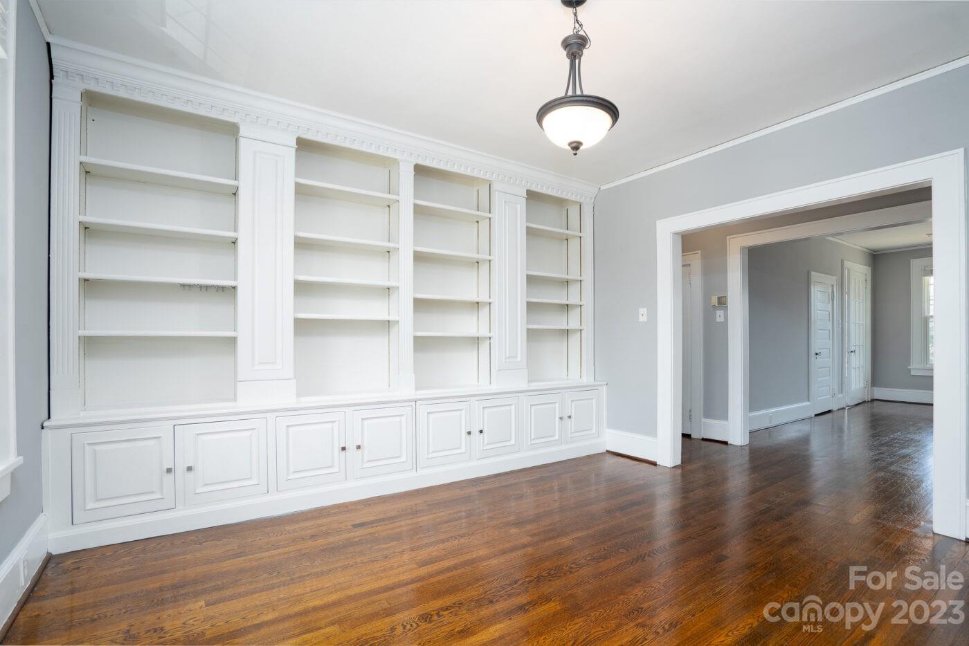 a view of an empty room with wooden floor and cabinets