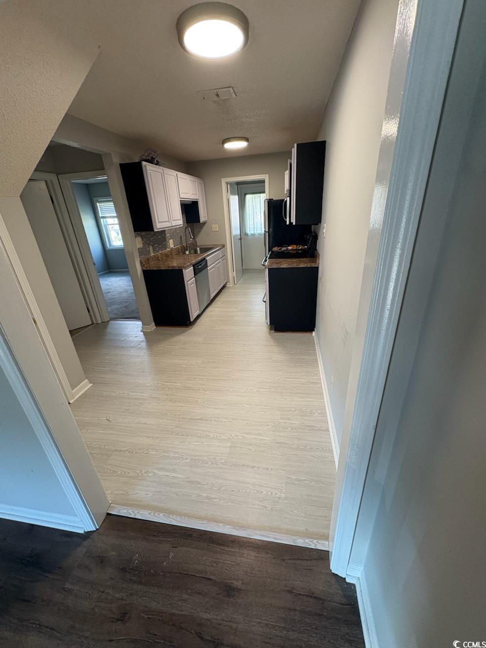 755 Burcale Road, Unit H2 Myrtle Beach, SC 29579 - Photo 4 of 15 Kitchen featuring light wood-type flooring, tasteful backsplash, dark countertops, dishwasher, and white cabinets