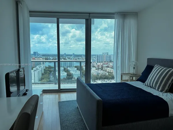 a bed sitting in a bedroom next to a window with wooden floor