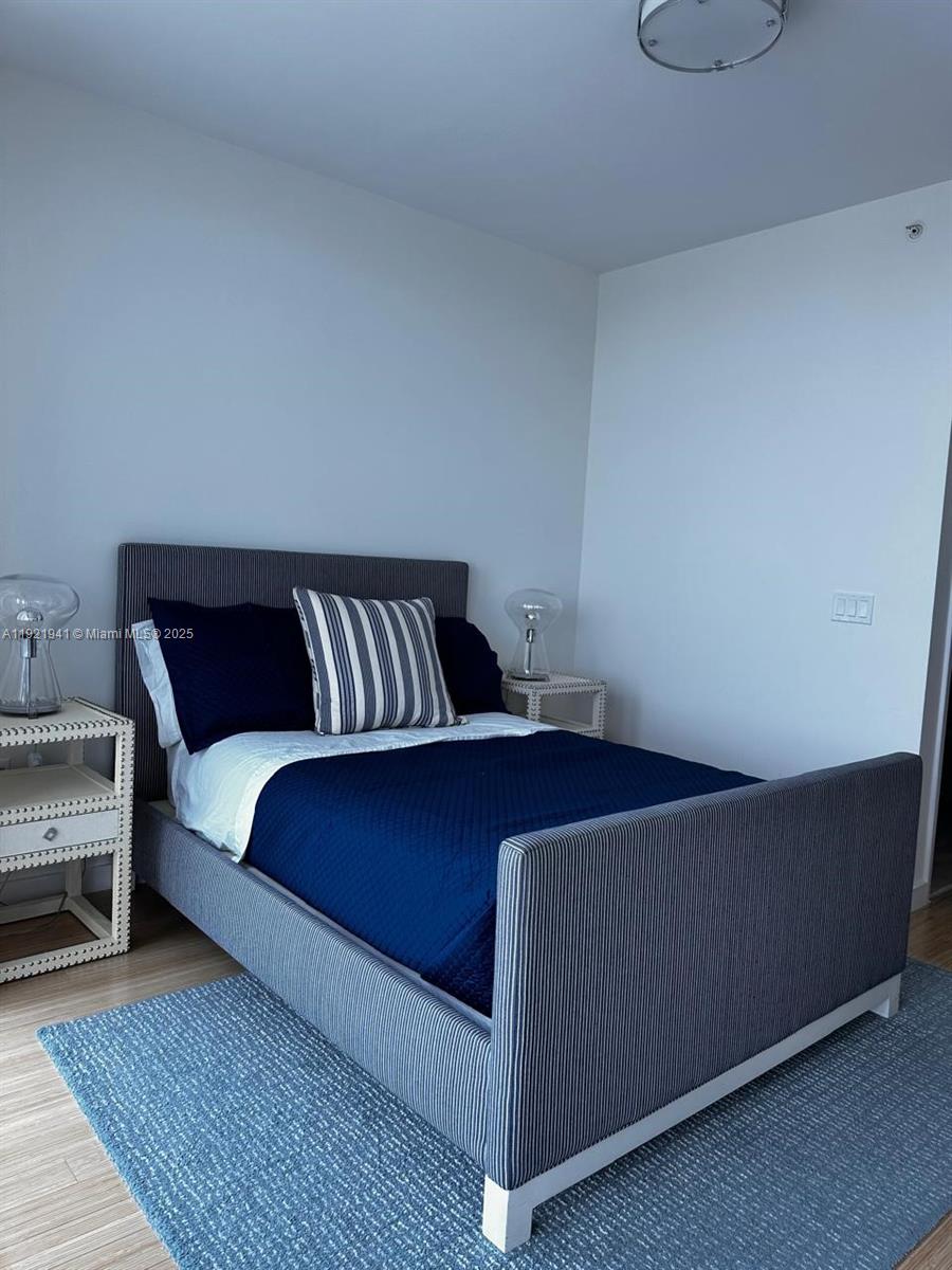 17001 Collins Avenue, Unit 2601 Sunny Isles Beach, FL 33160 - Photo 18 of 27 a bed sitting in a bedroom next to a window with wooden floor