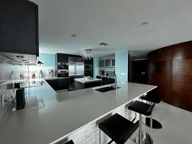 a kitchen with stainless steel appliances kitchen island granite countertop a refrigerator and cabinets