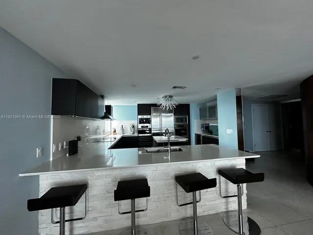 a kitchen with a refrigerator a stove a microwave oven and a sink with wooden floor