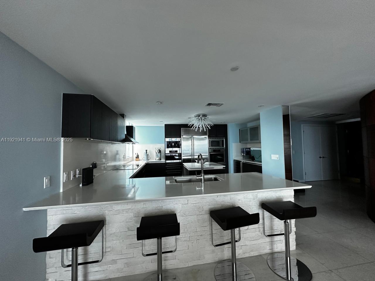 17001 Collins Avenue, Unit 2601 Sunny Isles Beach, FL 33160 - Photo 26 of 27 a kitchen with stainless steel appliances kitchen island granite countertop a refrigerator and cabinets