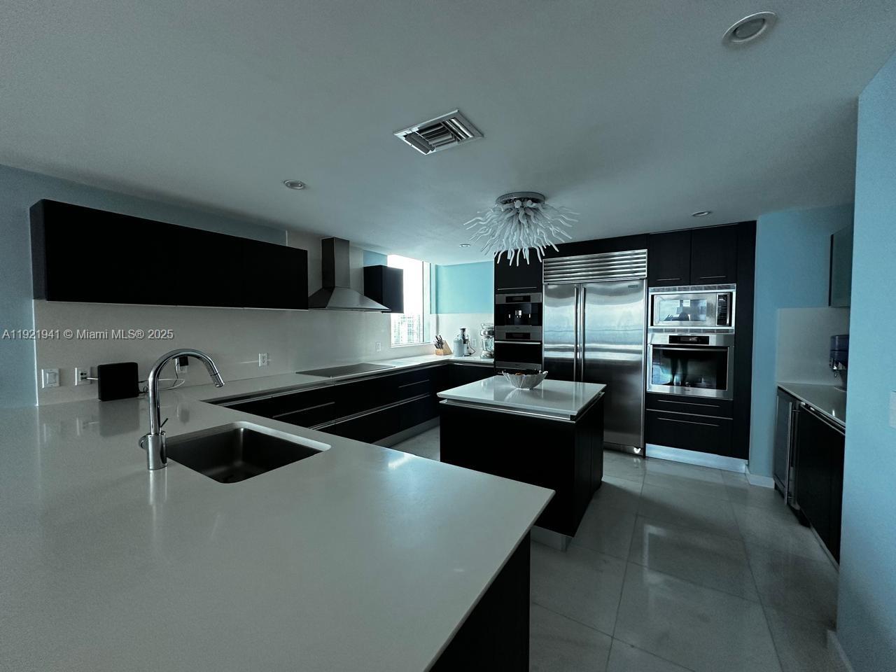 17001 Collins Avenue, Unit 2601 Sunny Isles Beach, FL 33160 - Photo 27 of 27 a kitchen with a refrigerator a stove a microwave oven and a sink with wooden floor