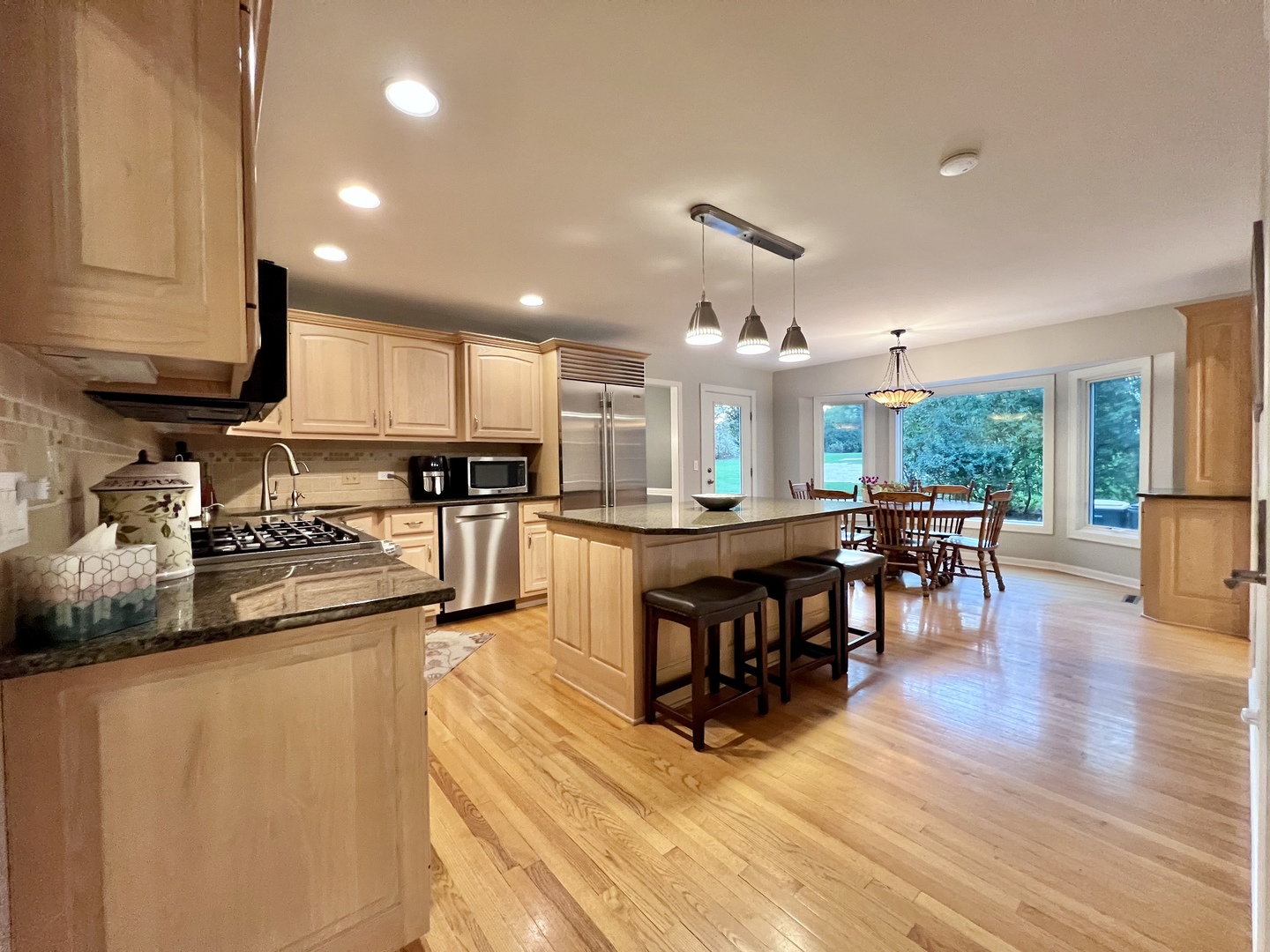 4111 Steeple Run Crystal Lake, IL 60014 - Photo 3 of 50 a kitchen with stainless steel appliances granite countertop a stove top oven a sink a dining table and chairs with wooden floor