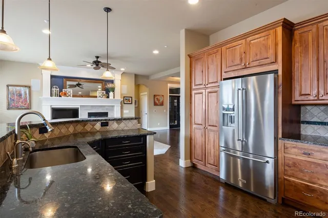 a kitchen with stainless steel appliances granite countertop a refrigerator a stove and a sink with wooden floor