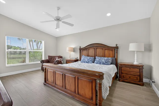 a bedroom with a bed next to a large window with wooden floor