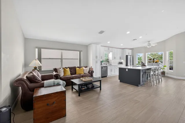 a living room with furniture wooden floor and a kitchen