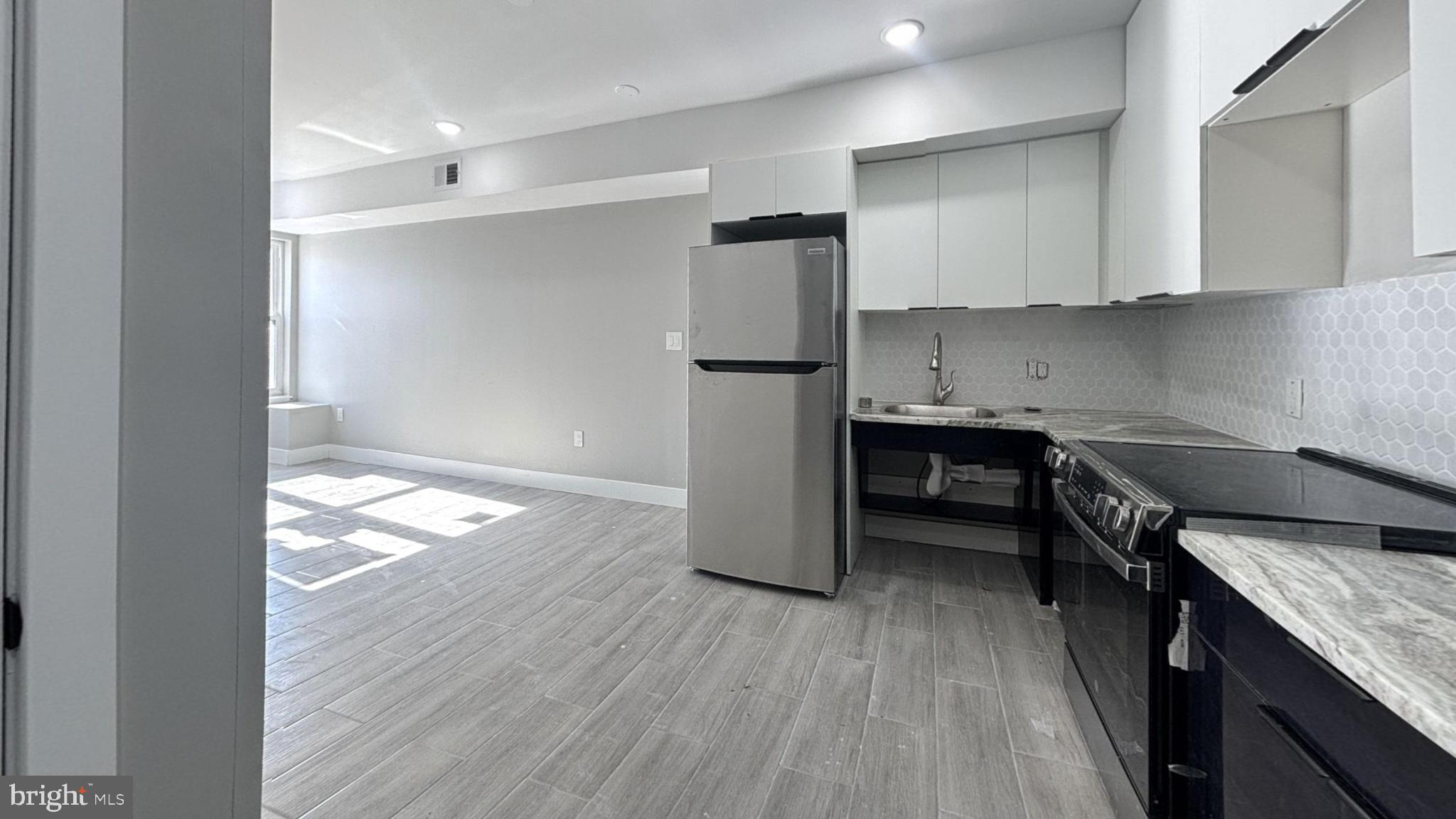5341 Chestnut Street, Unit 1 Philadelphia, PA 19139 - Photo 4 of 4 a kitchen with granite countertop white cabinets and wooden floor
