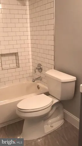 a white toilet sitting next to a bath tub