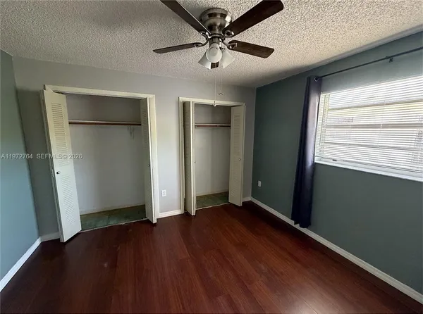 an empty room with wooden floor closet and windows