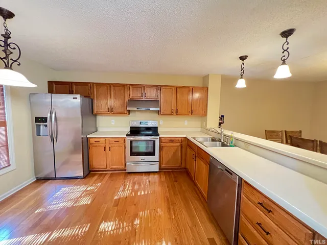 a kitchen with stainless steel appliances a sink cabinets and wooden floor