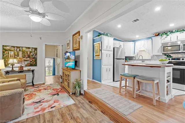 a kitchen with stainless steel appliances granite countertop a refrigerator a sink dishwasher a stove and white cabinets with wooden floor