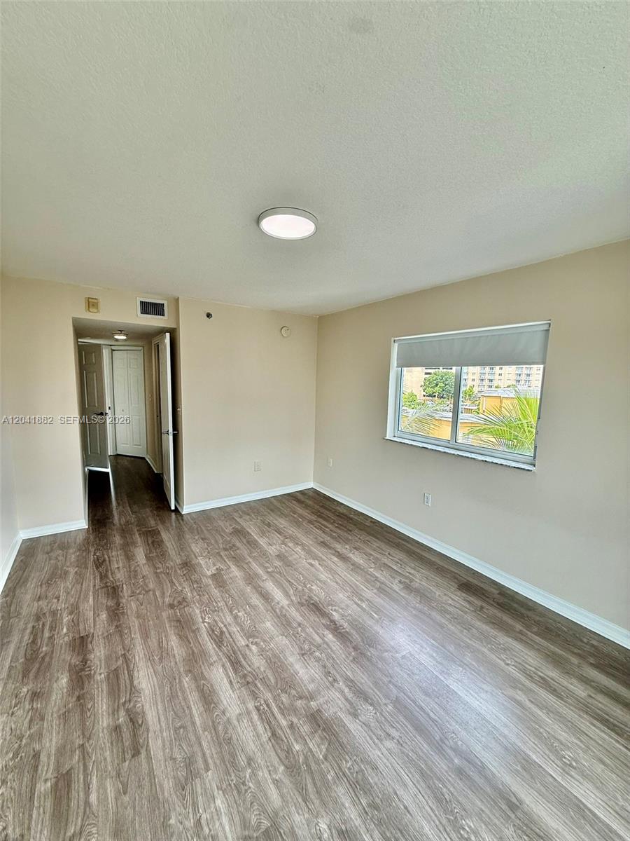 2475 Northwest 16th St Road, Unit 418 Miami, FL 33125 - Photo 17 of 27 a view of empty room with wooden floor and fan