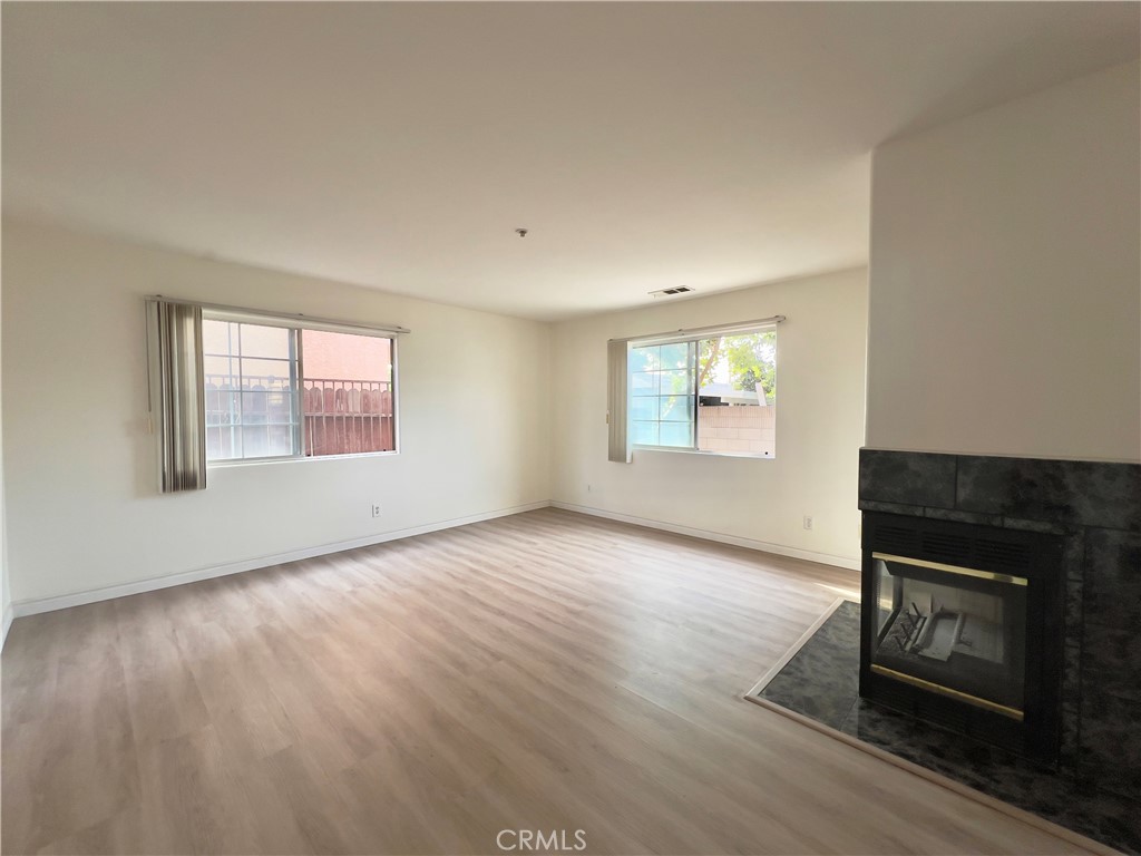 12143 Ferris Road El Monte, CA 91732 - Photo 6 of 41 an empty room with wooden floor fireplace and windows