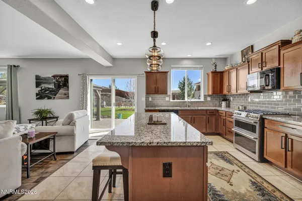 a kitchen with stainless steel appliances granite countertop a stove top oven a sink dishwasher a dining table and chairs with wooden floor