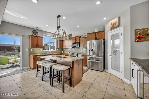 a kitchen with stainless steel appliances granite countertop a stove top oven a refrigerator a sink and a dining table