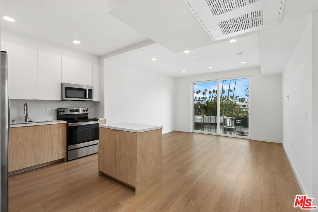 4406 Fulton Avenue, Unit 404 Sherman Oaks, CA 91423 - Photo 6 of 30 a kitchen with wooden floors and stainless steel appliances