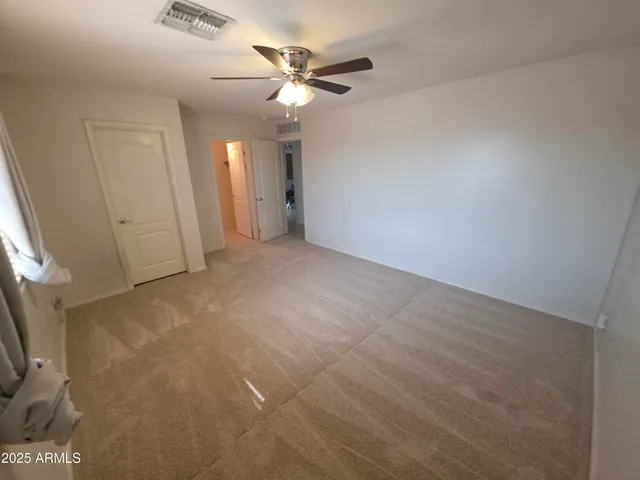 an empty room with ceiling fan and window