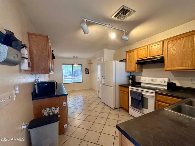 a kitchen with granite countertop a stove a sink and a refrigerator