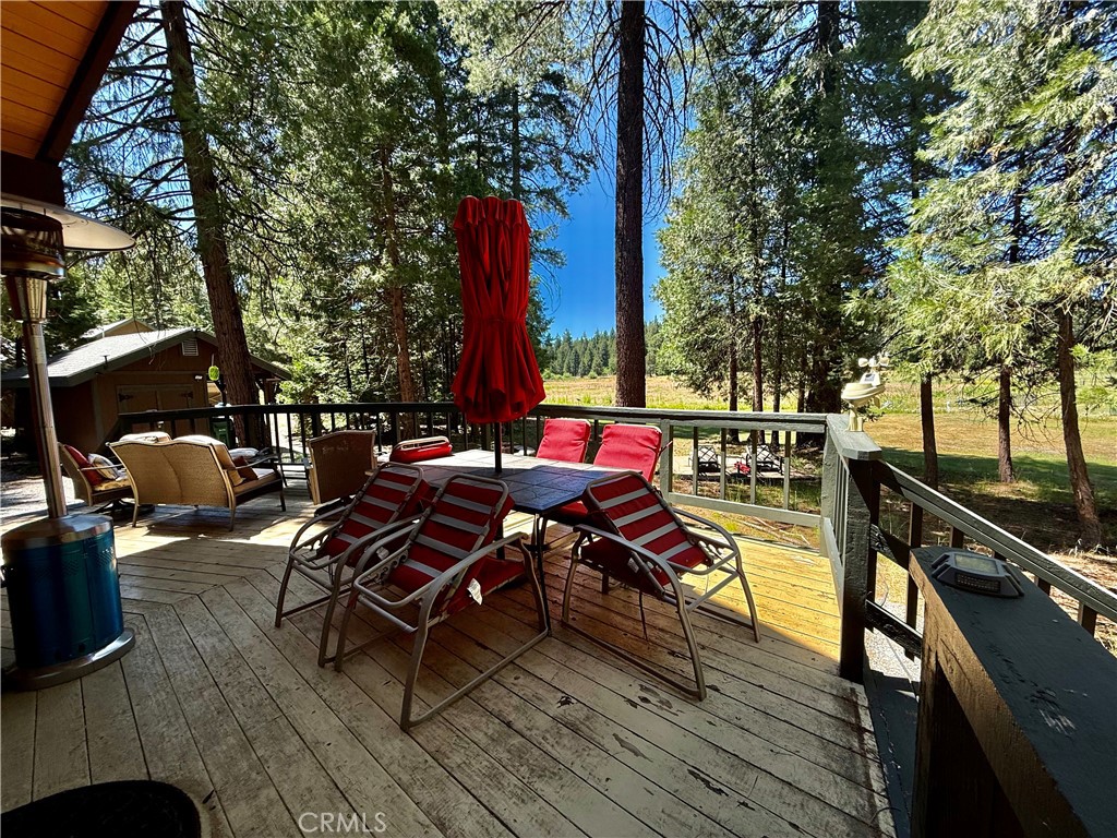 9312 Mountain Meadow Road Shingletown, CA 96088 - Photo 31 of 44 a view of a roof deck with table and chairs a barbeque with wooden floor and fence