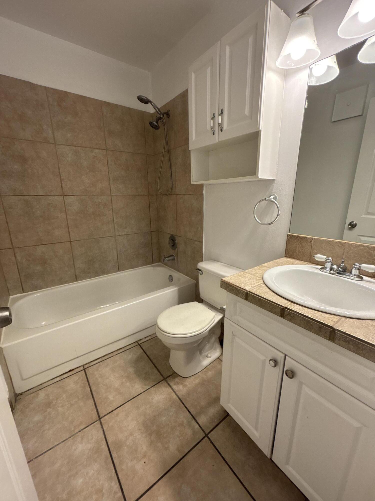 1830 Abbey Road, Unit 105 West Palm Beach, FL 33415 - Photo 8 of 12 a bathroom with a granite countertop sink toilet a mirror and bathtub