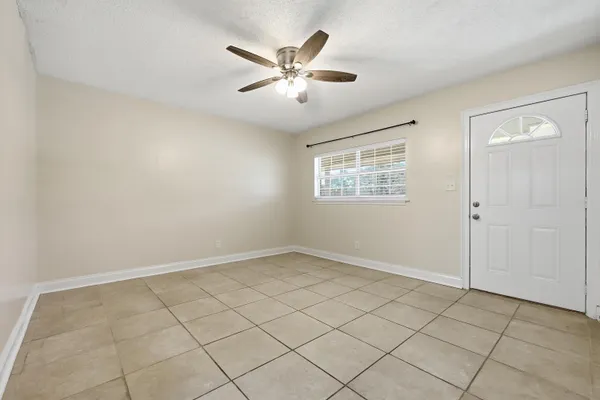 an empty room with windows and ceiling fan
