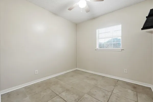 an empty room with a chandelier fan and windows