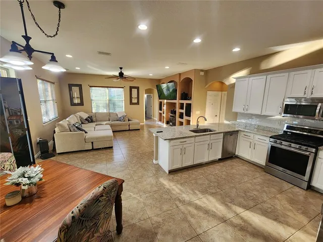 a living room with stainless steel appliances furniture kitchen view and a chandelier