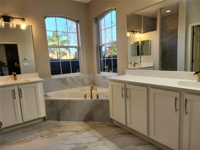 a bathroom with a tub a sink a mirror and a shower
