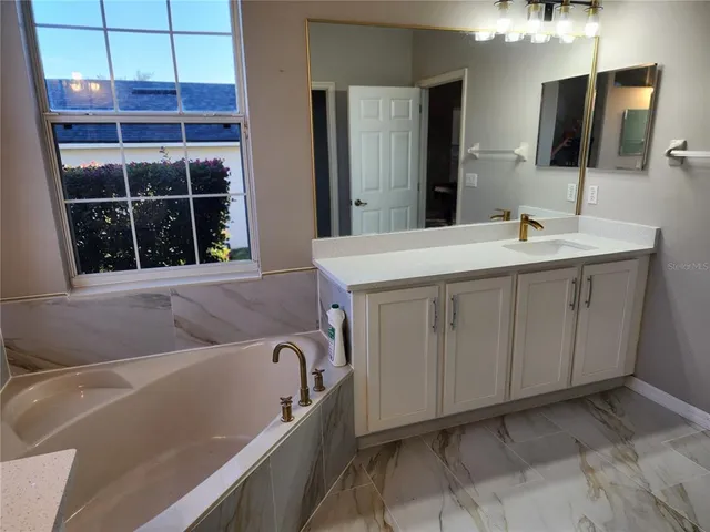 a bathroom with a tub sink and mirror