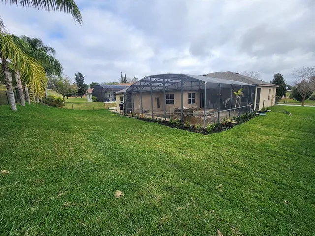 a view of a house with a big yard plants and large trees