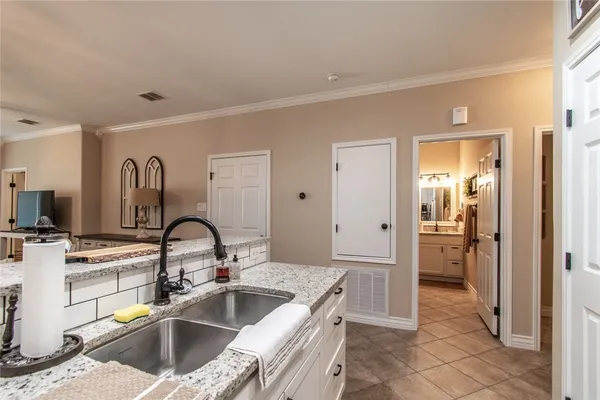 a kitchen with stainless steel appliances kitchen island granite countertop a table chairs in it and white cabinets