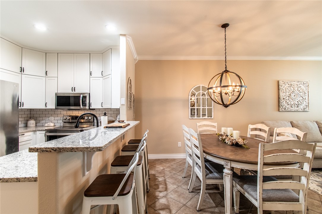 1117 Ninth Street, Unit 803 Port Aransas, TX 78373 - Photo 10 of 27 a kitchen with stainless steel appliances kitchen island granite countertop a table chairs in it and white cabinets